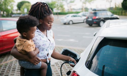 A woman with a toddler is charging an electric car 